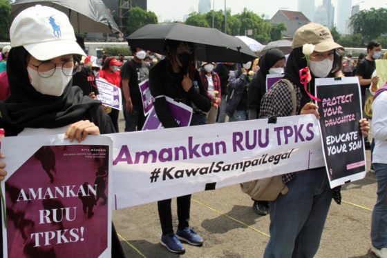 dua orang perempuan memegang spanduk bertuliskan "Amankan RUU TPKS"