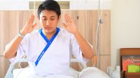 Seorang pria yang sedang sakit melaksanakan tata cara sholat duduk